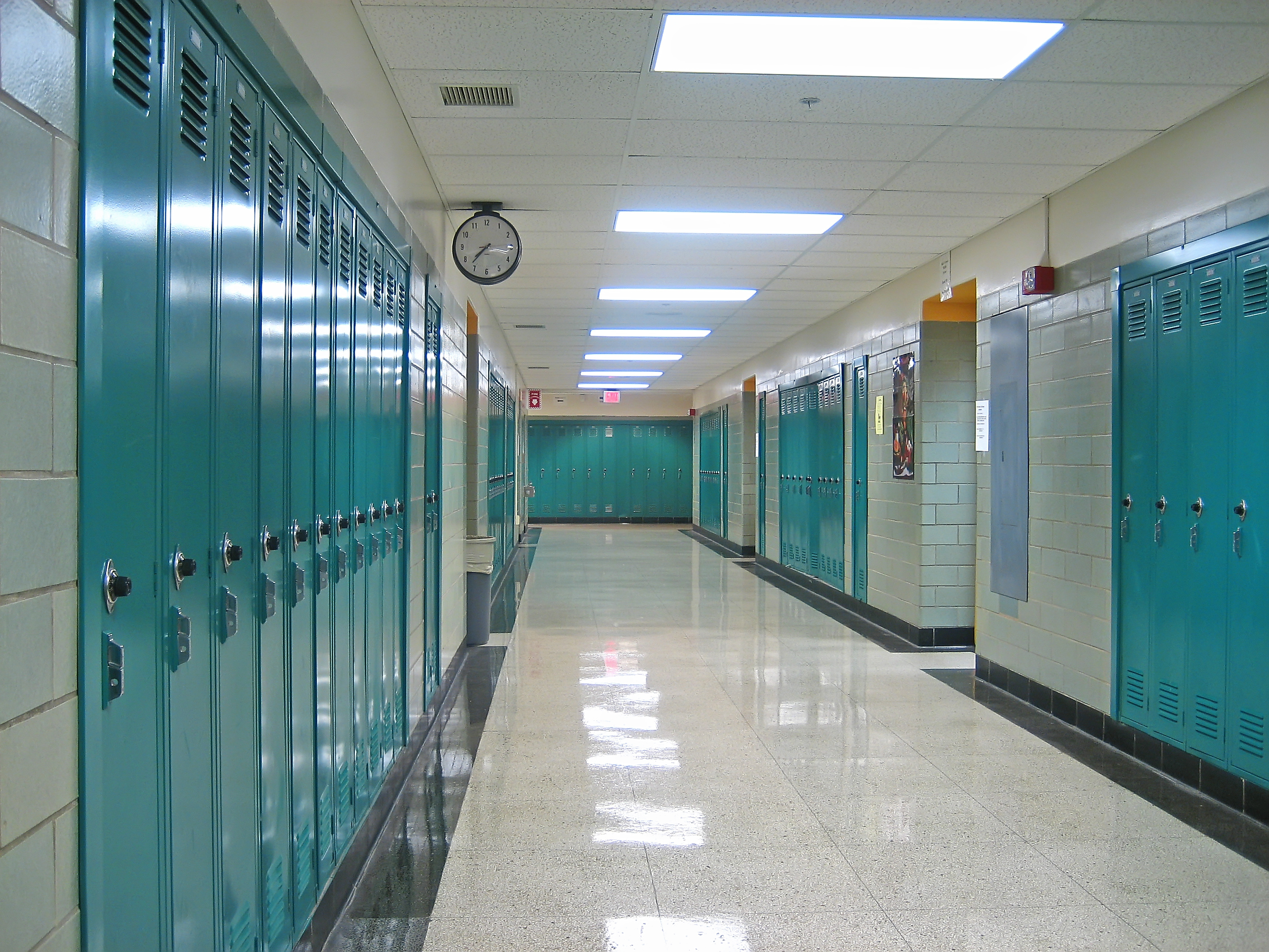 A hallway with many lockers and a clock.