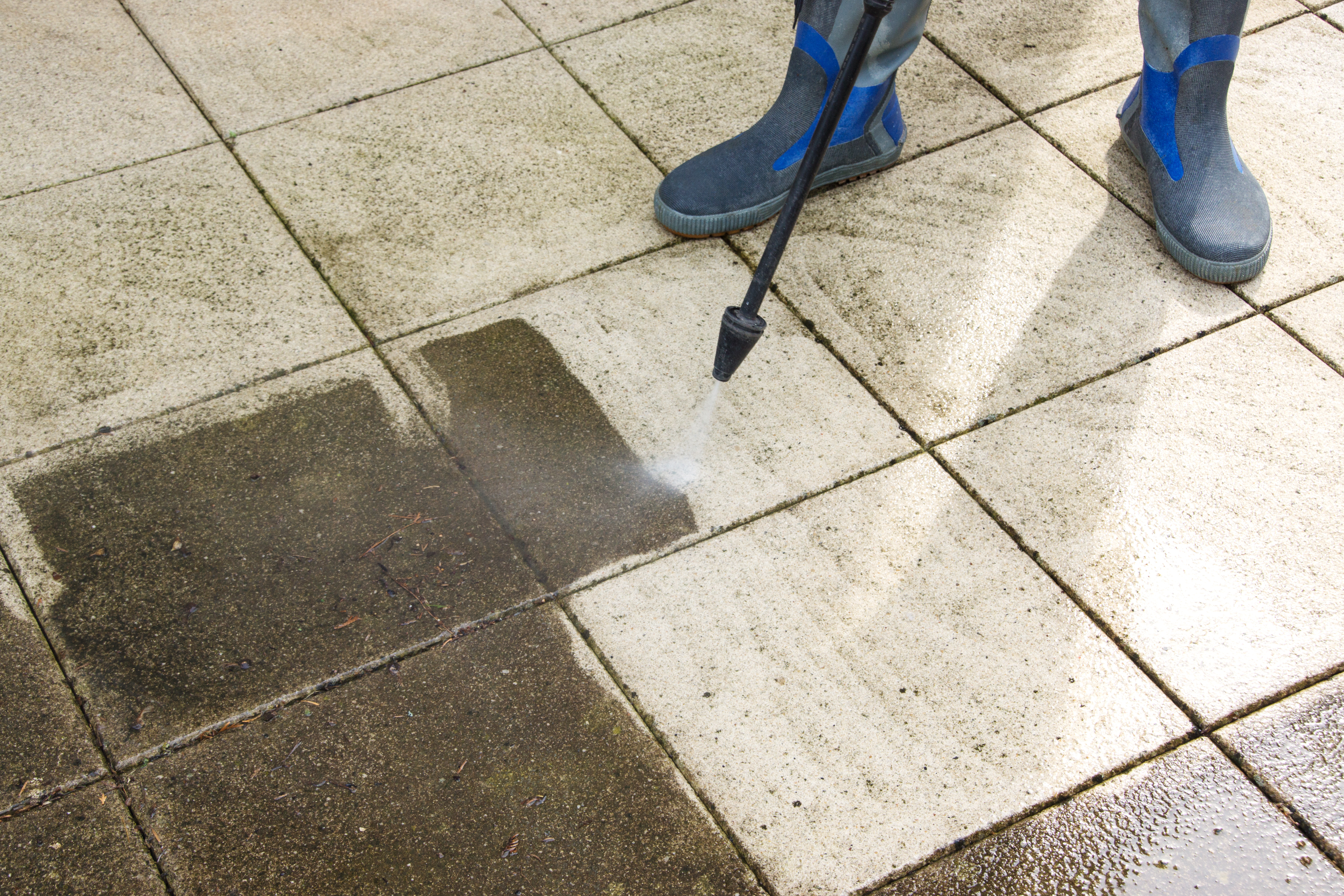 A person using a power washer on the floor.